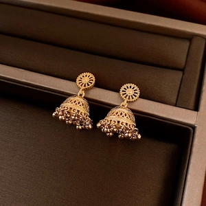 Macro shot of 14K gold plated Jhumka bell earrings with hollow carvings and beaded tassels