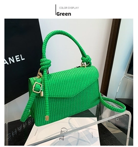 Detail of green woven handbag with knot handle design and golden metal buckle