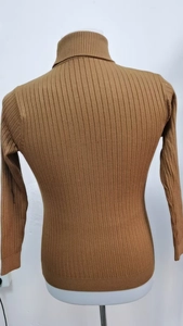 Dettaglio macro del maglione a collo alto caramello con trama a coste verticali
