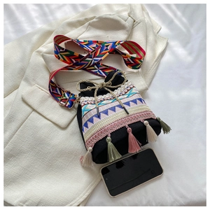 Detail of ethnic embroidery and colorful tassels on a black canvas bucket bag