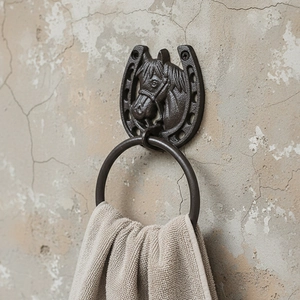 Rustic cast iron horseshoe towel ring with horse head design on a textured wall