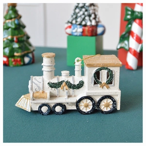 Macro view of ivory white resin Christmas train ornament with golden accents and green wreaths