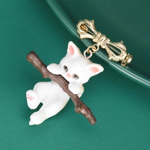 Macro shot of a cute white cat hugging a brown branch brooch with a golden bow pin
