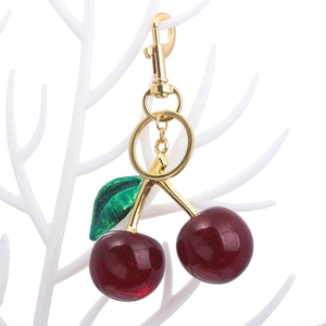Detailed view of dark red glitter cherry keychain with green leaf and golden clasp