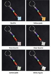 Detail of six Merkaba star keychains with rainbow chakra beads on black background