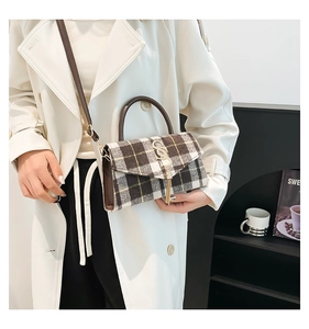 Detail view of plaid tassel handbag worn with an elegant beige trench coat