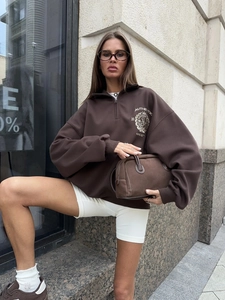 Detail of vintage dark brown half-zip sweatshirt with chest logo and white bike shorts
