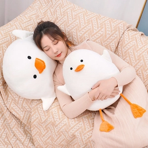 Young Asian model cuddling two cute white duck plush toys on a cozy patterned sofa