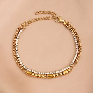 Detail of gold double-layered bracelet with zircon stones and cylinder beads on satin