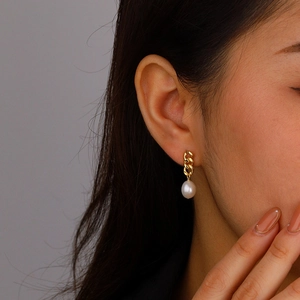 Close-up of 18K gold-plated Cuban chain earring with a Baroque pearl on the ear