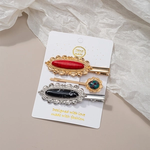 Detailed view of three vintage hair clips with red, black, and turquoise textured stones