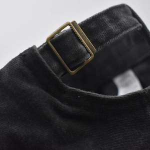 Close-up of adjustable antique brass buckle on black washed cotton baseball cap