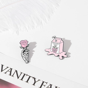 Detail of pink skull rose and fresh boy tears milk carton enamel pins on feathers
