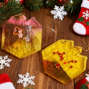 Detailed view of yellow house-shaped resin charms with glitter on a festive wooden background