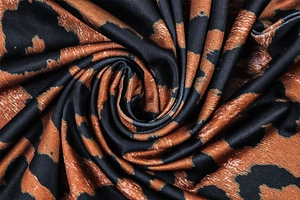 Macro detail of glossy leopard print fabric with smooth satin texture and bronze tones