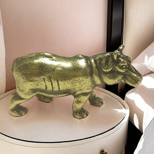 Macro detail of a solid brass hippo figurine showing hammered metal texture and golden gloss