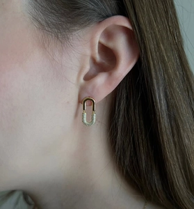 Close-up of elegant gold U-shaped earrings with micro-inlaid zircon on a model