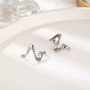 Macro shot of silver wave-shaped titanium steel earrings on a clean display tray