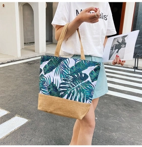 Outdoor shot of canvas tote bag with green tropical leaf prints and brown trim