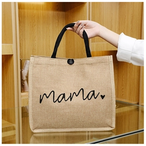 Detail of jute tote bag with black mama script and sturdy woven handles on wooden stand