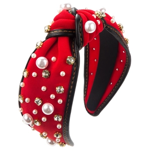 Détail d'un serre-tête baroque rouge avec perles, strass et coutures contrastées