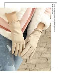 Close-up of beige faux suede gloves for women featuring a gold decorative metal tag on the cuff