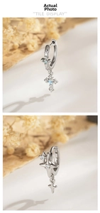 Macro detail of silver cross and star earrings with blue gemstone and screw back