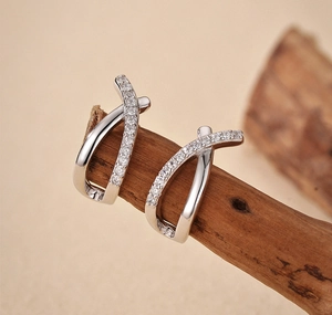 Detail of silver S925 cross earrings with micro-inlaid diamonds on a wooden branch
