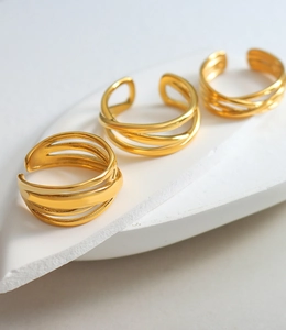 Macro detail of three layered gold-plated crisscross stackable rings on stone display