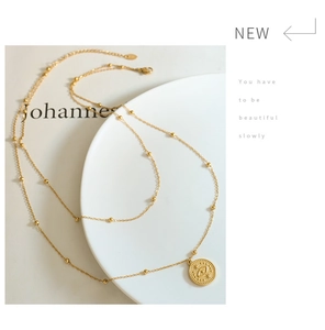 Detail of 18k gold double-layer necklace with evil eye pendant on a white ceramic plate