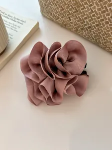 Détail de la pince à cheveux élégante en mousseline rose poudré sur fond de magazine chic