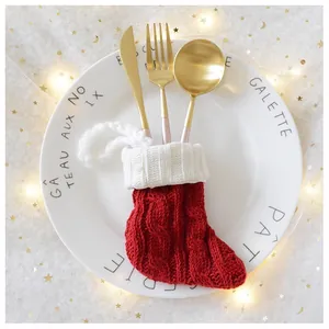 Macro detail of red and white knit Christmas stocking cutlery holder on a white dinner plate