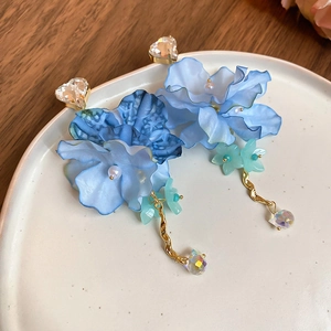 Detail of blue chiffon flower earrings with crystal heart stud on a ceramic plate