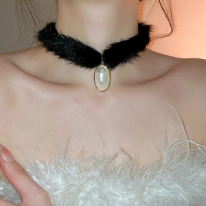 Detail of elegant black faux fur choker with teardrop pearl pendant and gold metal trim