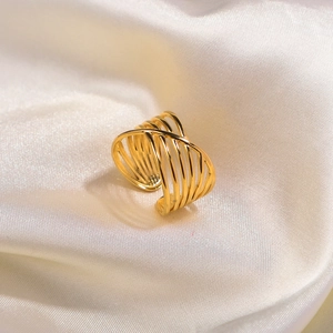 Close-up of golden multi-layer crisscross ring on soft white silk fabric background