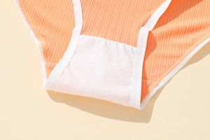 Macro shot of orange ribbed polyester panties showing breathable double-layer crotch detail