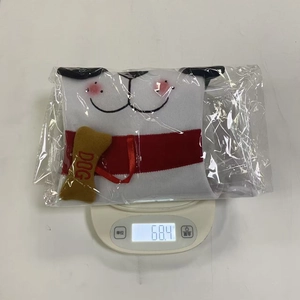 Close-up of a white plush dog Christmas stocking weighing 68.4g on a digital scale