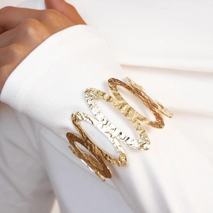 Detail of golden hammered texture on wide wavy bangle with premium metallic finish