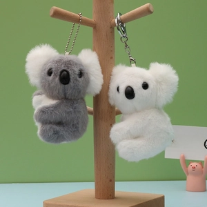 Cute koala plush keychain in grey and white hanging on a wooden stand with metal rings