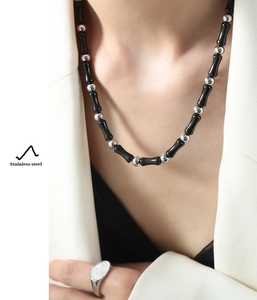 Detail of beaded necklace with black cylindrical beads and silver stainless steel accents