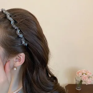 Sparkling wave-shaped rhinestone headband with pearl earrings on long wavy brown hair
