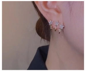 Close-up of triple star flower earrings in gold with sparkling white cubic zirconia