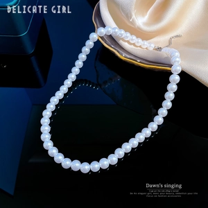 Close-up of elegant white pearl necklace on black reflective surface with silk background