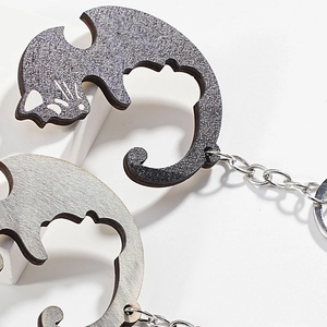 Macro detail of cat-shaped couple keychains with glitter and textured wood finish