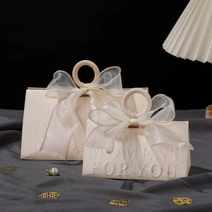 Detail of beige triangle wedding favor boxes with wooden handles and sheer tulle bows
