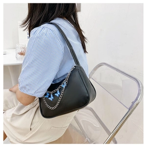 Detail of black crescent shoulder bag featuring silver chain and blue butterfly charms
