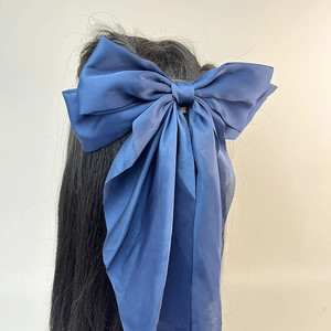 Vue détaillée d'une grande barrette à nœud en satin bleu avec de longs rubans