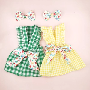 Detail of plaid pet dresses in green and yellow with floral bows and ruffled straps