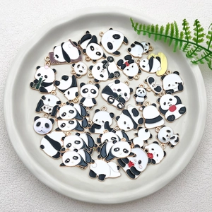 Close-up of assorted enamel panda charms for DIY jewelry on a white ceramic plate
