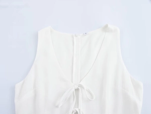 Detailed view of white V-neck top featuring sweet tie-bow design and ruffled edges
